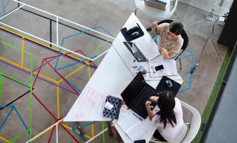 Two Women Sitting In Chairs Using Laptop Computers 2566573